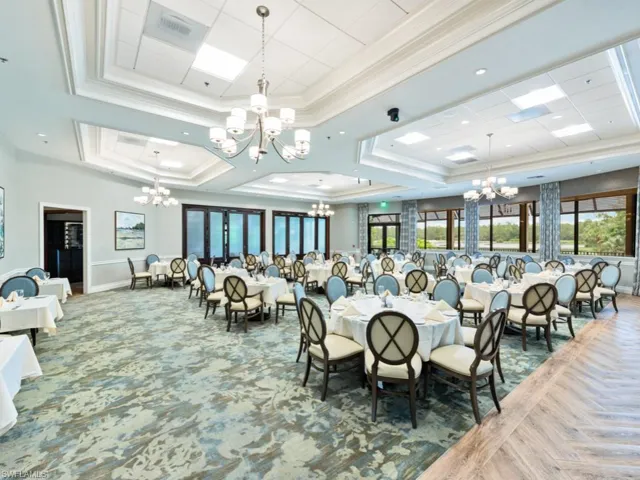 Dining area featuring a raised ceiling, crown molding, a chandelier, and parquet floors
