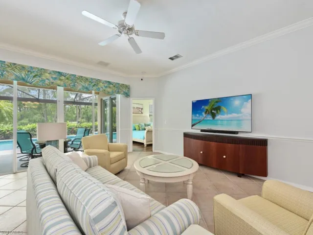Tiled living room with ornamental molding and ceiling fan