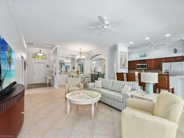 Tiled living room with ceiling fan with notable chandelier and crown molding