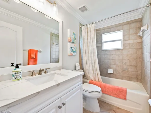 Full bathroom featuring tile patterned flooring, crown molding, toilet, vanity, and shower / bath combo with shower curtain
