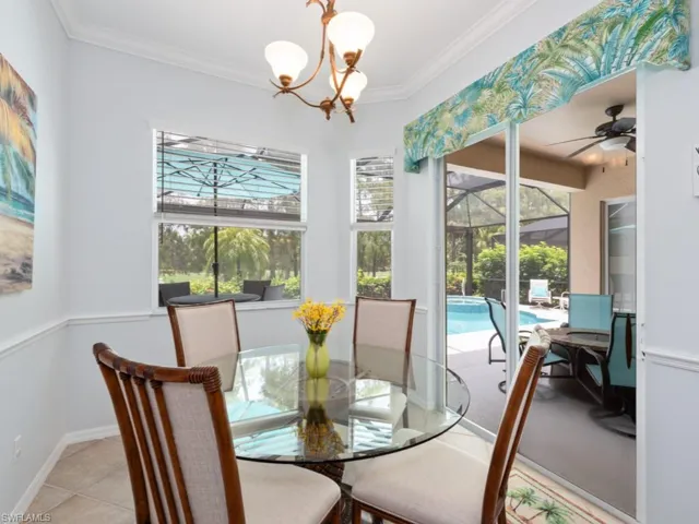 Dining space featuring light tile patterned floors, ceiling fan with notable chandelier, crown molding, and a wealth of natural light