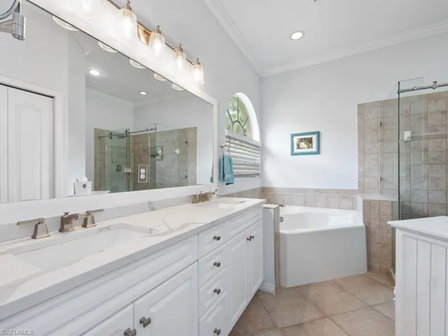 Bathroom featuring independent shower and bath, dual vanity, ornamental molding, and tile patterned flooring