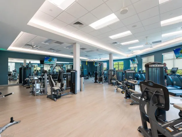 Gym with a tray ceiling, a drop ceiling, and light hardwood / wood-style floors