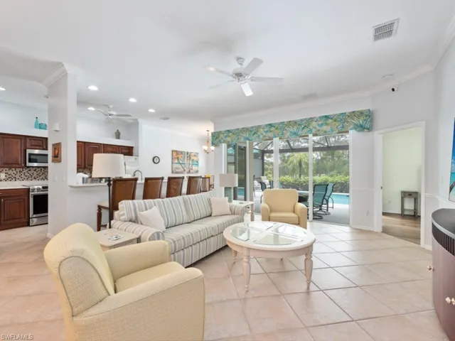 Living room with light tile patterned floors, ceiling fan, and crown molding