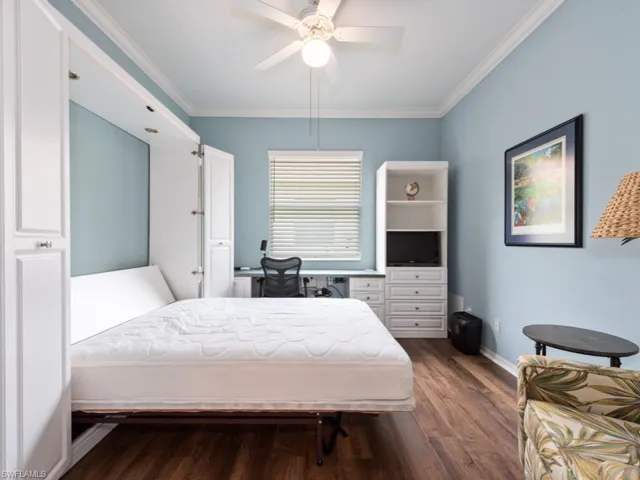 Bedroom featuring dark hardwood / wood-style floors, ornamental molding, and ceiling fan