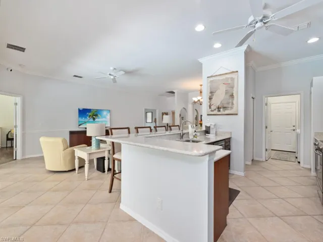 Kitchen featuring sink, ceiling fan with notable chandelier, light tile patterned floors, and crown molding