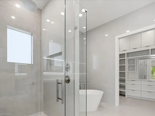 Bathroom with a stall shower, a soaking tub, a walk in closet, and recessed lighting