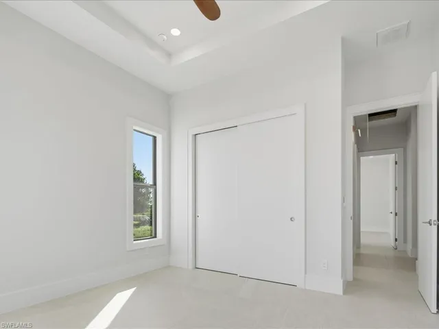Unfurnished bedroom featuring a closet, attic access, and ceiling fan