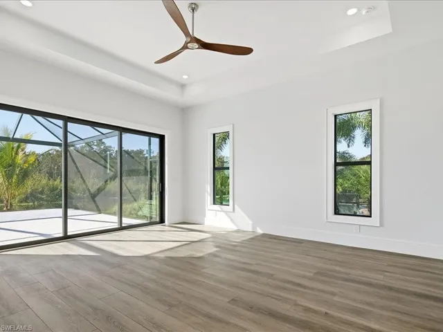Empty room with wood finished floors, a raised ceiling, a ceiling fan, and recessed lighting