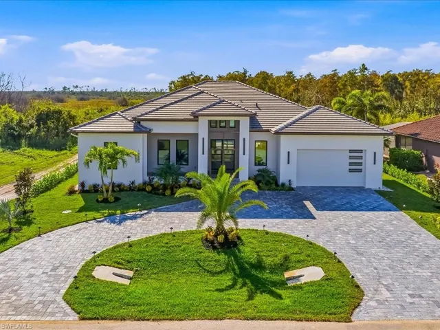 View of front of property with decorative driveway, a front yard, and stucco siding