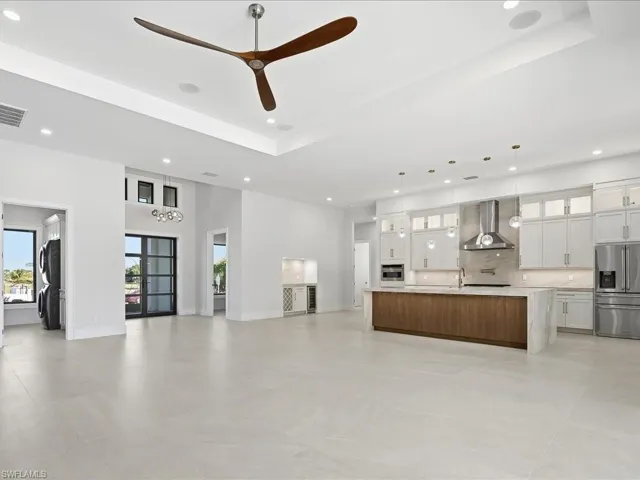 Unfurnished living room featuring recessed lighting, a chandelier, a tray ceiling, and a ceiling fan