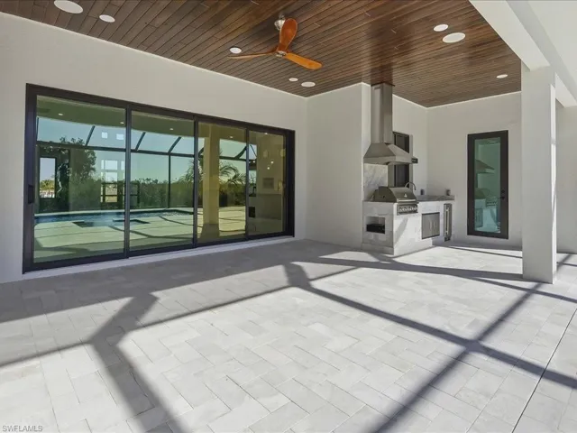 View of patio with exterior kitchen, ceiling fan, and glass enclosure