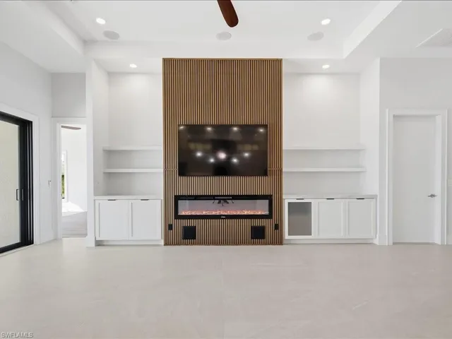 Unfurnished living room with a ceiling fan, a glass covered fireplace, recessed lighting, and built in features