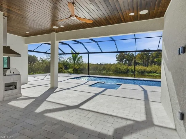 View of pool with glass enclosure, a sunroom, a patio area, and a pool with connected hot tub
