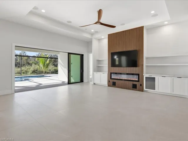 Unfurnished living room featuring built in shelves, ceiling fan, recessed lighting, and a glass covered fireplace