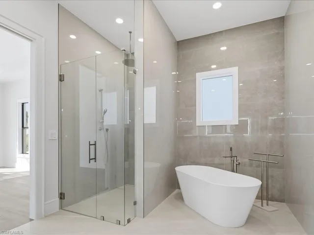 Bathroom featuring a soaking tub, a shower stall, recessed lighting, healthy amount of natural light, and tile walls