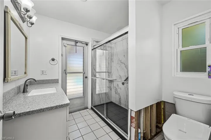 Pool Bathroom with tile patterned flooring, a shower stall, toilet, and vanity