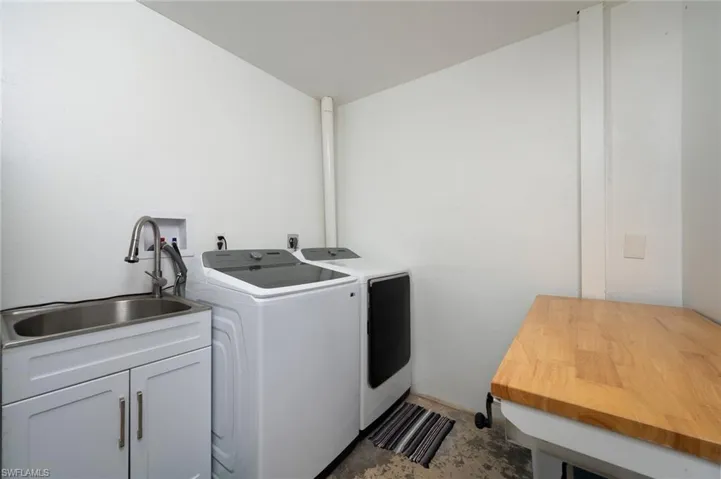 Clothes washing area with washer and clothes dryer, a sink, and cabinet space