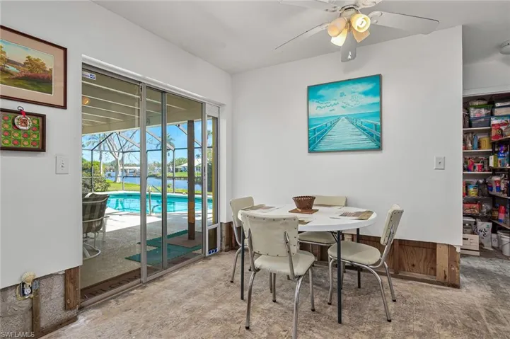 Dining area featuring a sunroom and a ceiling fan looking out on the pool and river