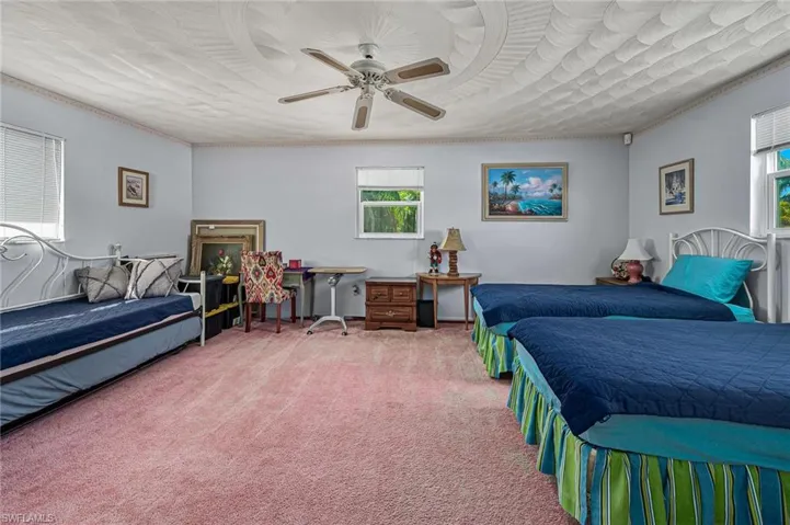 Carpeted 2nd bedroom upstairs featuring ceiling fan and ornamental molding and cofferered ceiling.