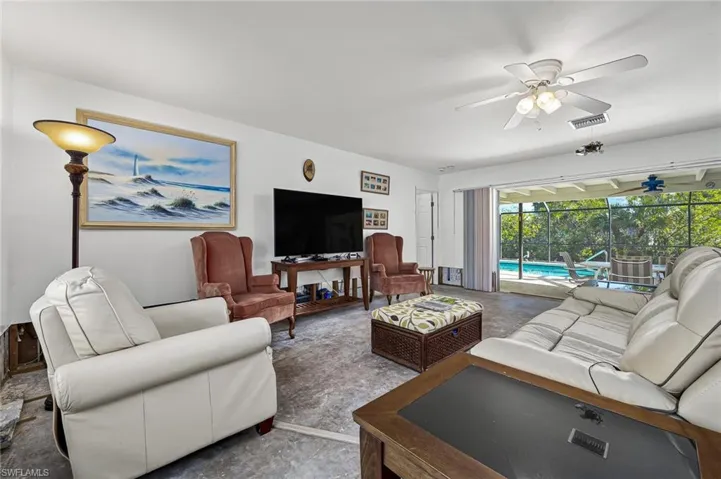 Living area featuring a lots of sunlight with pocketed sliding glass doors leading out to the screened pool area.