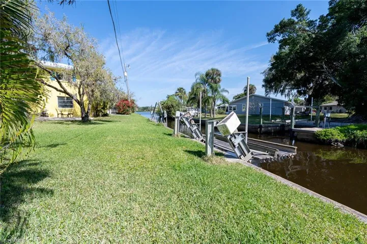 View of backyard on the canal with the river 2 homes down, featuring a boat lift and davits.