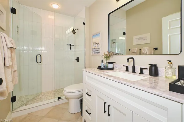 Full bath featuring vanity, a stall shower, and light tile patterned flooring
