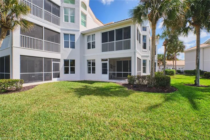 Rear view of property featuring a sunroom, stucco siding, a yard, and a balcony