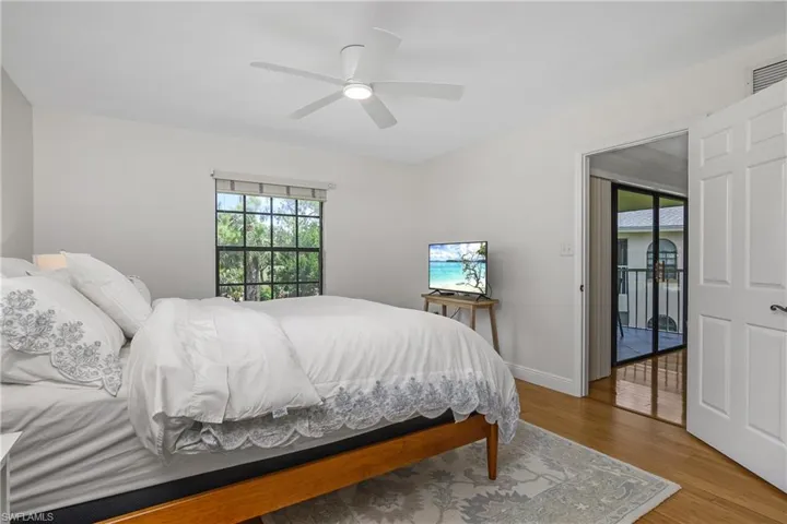 Primary Bedroom with wood finished floors, multiple windows, and a ceiling fan, tv and queen size bed