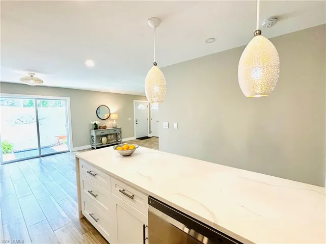 Kitchen features a large peninsula, tasteful backsplash, light granite countertops, white cabinetry