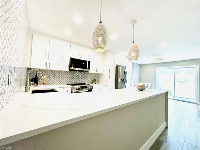 Kitchen featuring new stainless steel appliances, light  granite countertops, decorative backsplash, white cabinetry, and recessed lighting