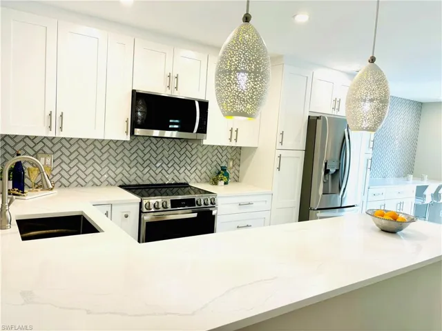 Kitchen featuring all  new stainless appliances, white cabinetry, light wood-style tile floors, granite  countertops, and pendant lighting