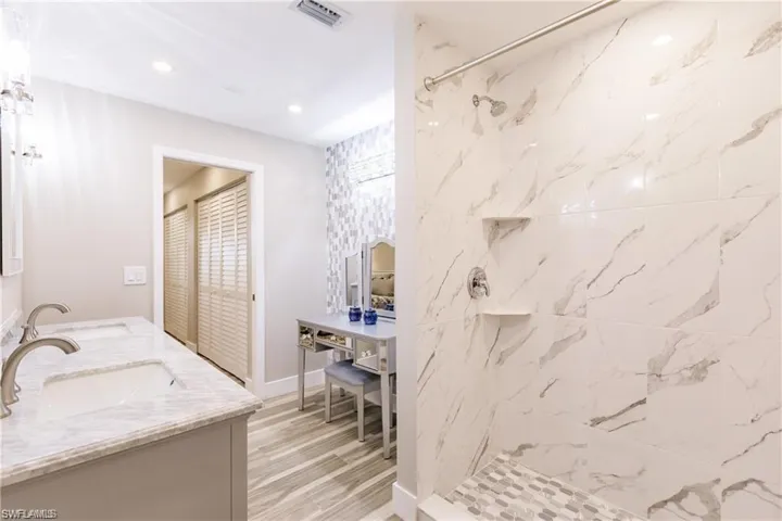 Primary ensuite bathroom featuring expansive dual sink vanity, dual mirrors,  tile flooring