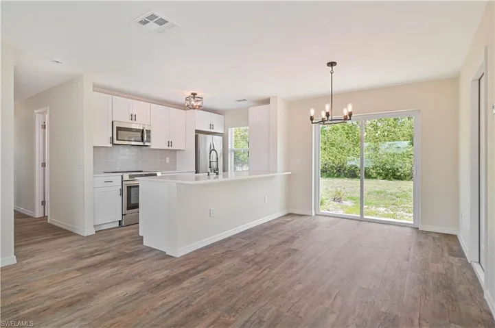 Kitchen featuring stainless steel appliances, a chandelier, wood finished floors, and white cabinets