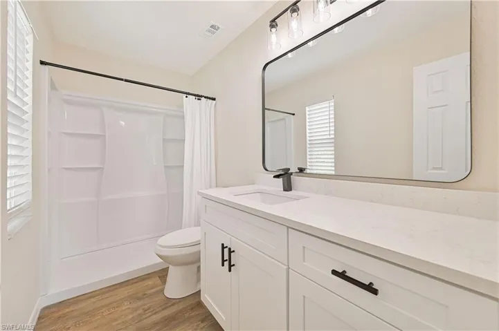 Full bath with wood finished floors, toilet, a shower with shower curtain, and vanity