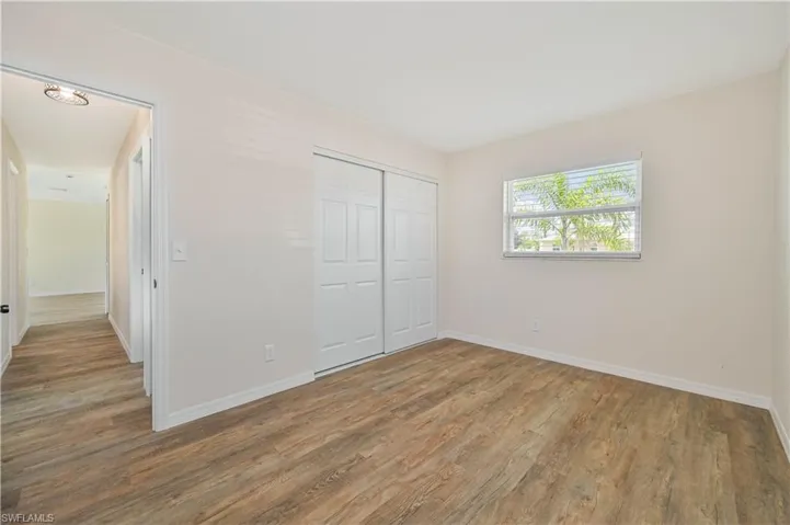 Unfurnished bedroom featuring wood finished floors, baseboards, and a closet