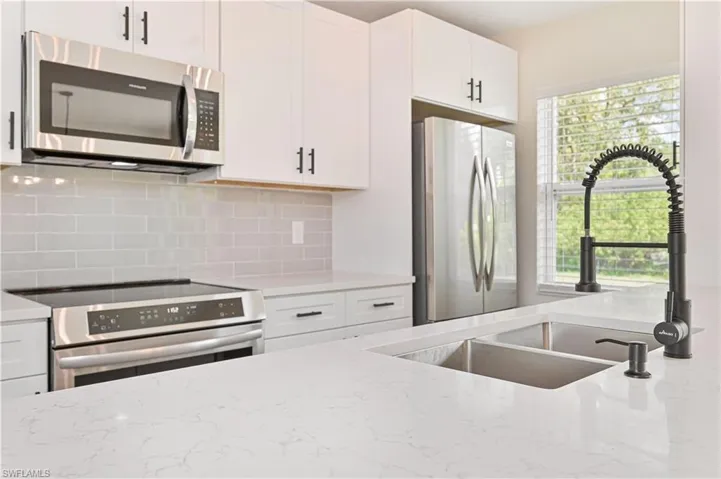 Kitchen with stainless steel appliances, a sink, healthy amount of natural light, and tasteful backsplash