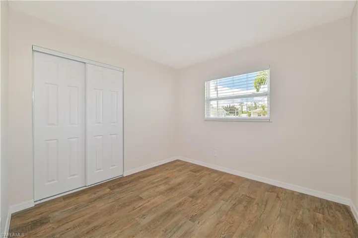 Unfurnished bedroom with wood finished floors, baseboards, and a closet