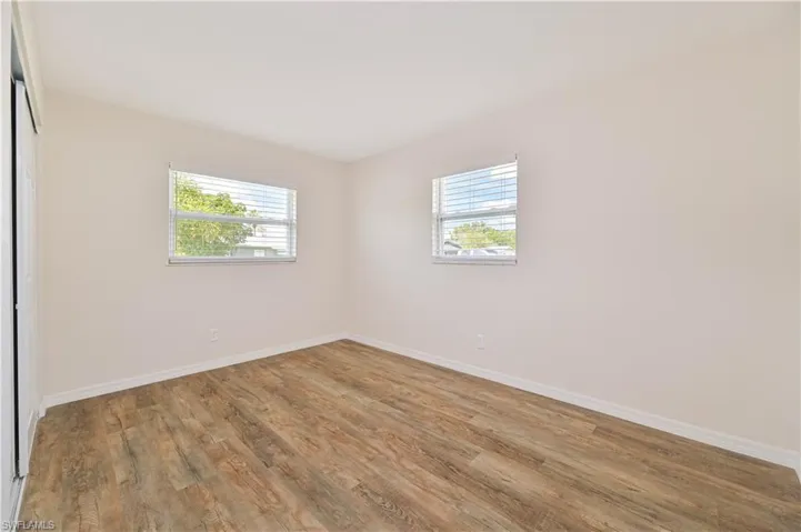 Unfurnished room with healthy amount of natural light, wood finished floors, and baseboards