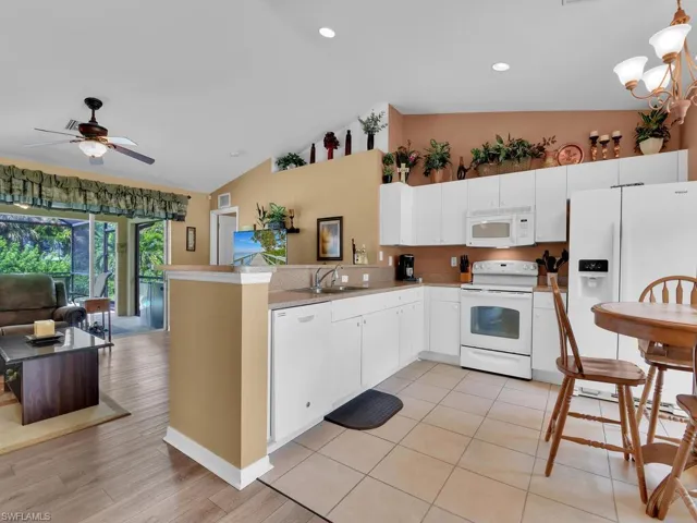 Kitchen with vaulted ceiling, kitchen peninsula, and white appliances