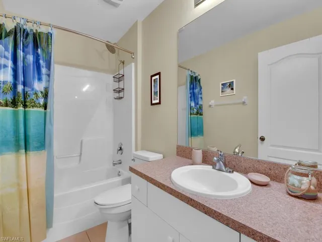 Full bathroom with shower / bathtub combination with curtain, tile flooring, toilet, and large vanity