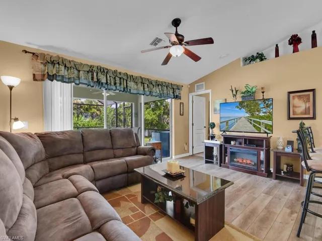 Living room with ceiling fan, vaulted ceiling, and light hardwood / wood-style flooring
