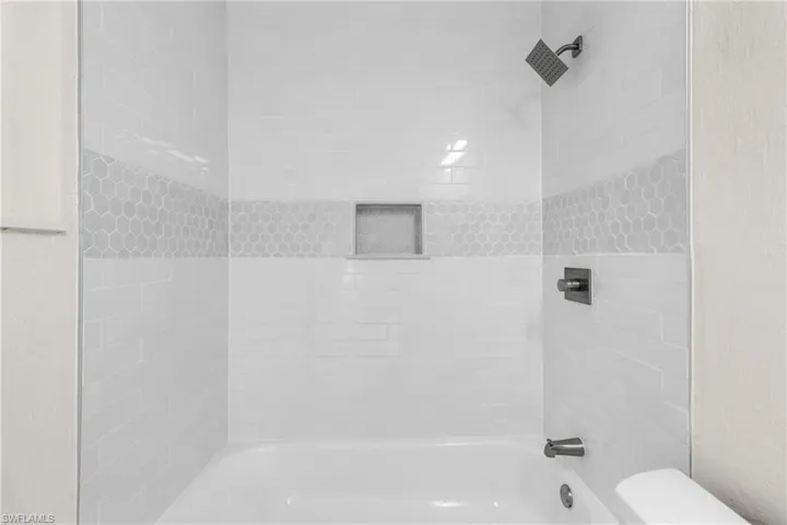Full bathroom featuring shower / bathtub combination and a textured wall