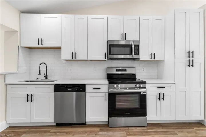 Kitchen featuring stainless steel appliances, light countertops, decorative backsplash, and light wood-type flooring
