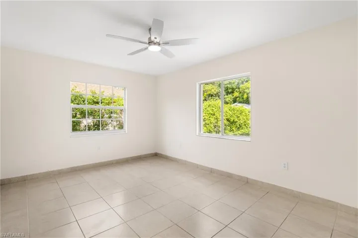 Spare room with healthy amount of natural light, light tile patterned floors, and ceiling fan