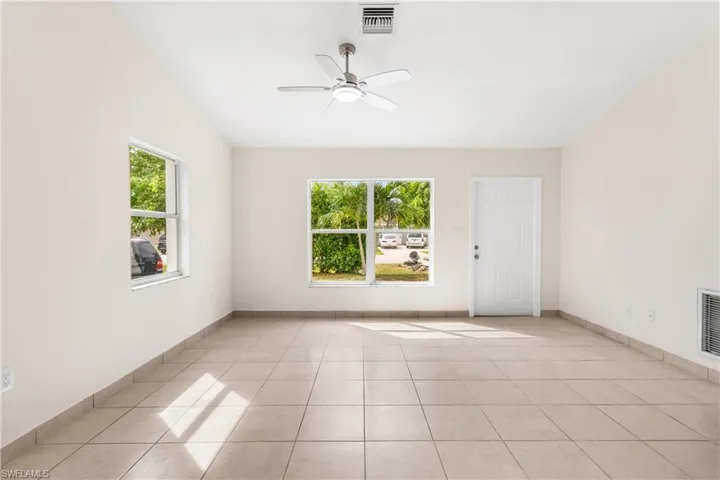 Spare room with healthy amount of natural light, light tile patterned floors, and a ceiling fan