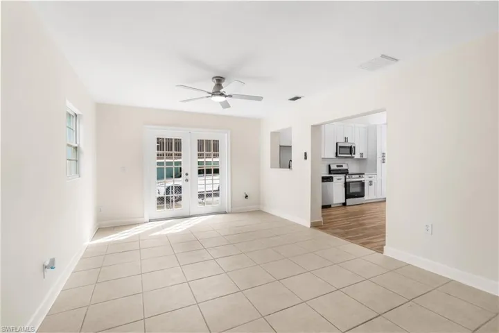 Spare room with light tile patterned floors, french doors, and ceiling fan