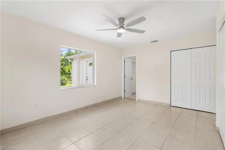 Unfurnished bedroom with light tile patterned flooring, a closet, and a ceiling fan