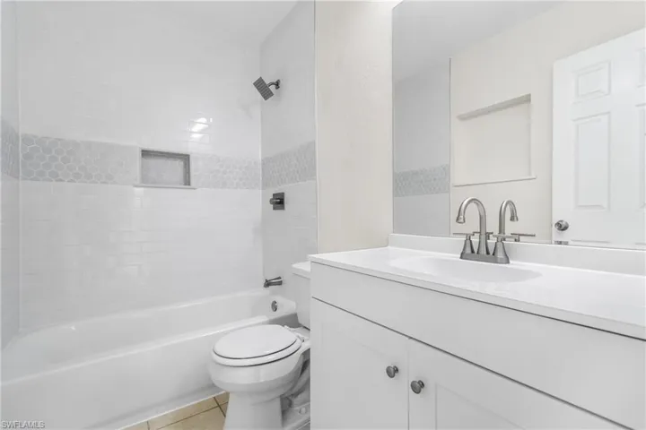 Bathroom featuring tile patterned flooring, vanity, and tub / shower combination