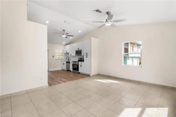 Unfurnished living room featuring recessed lighting, lofted ceiling, light tile patterned floors, and a ceiling fan